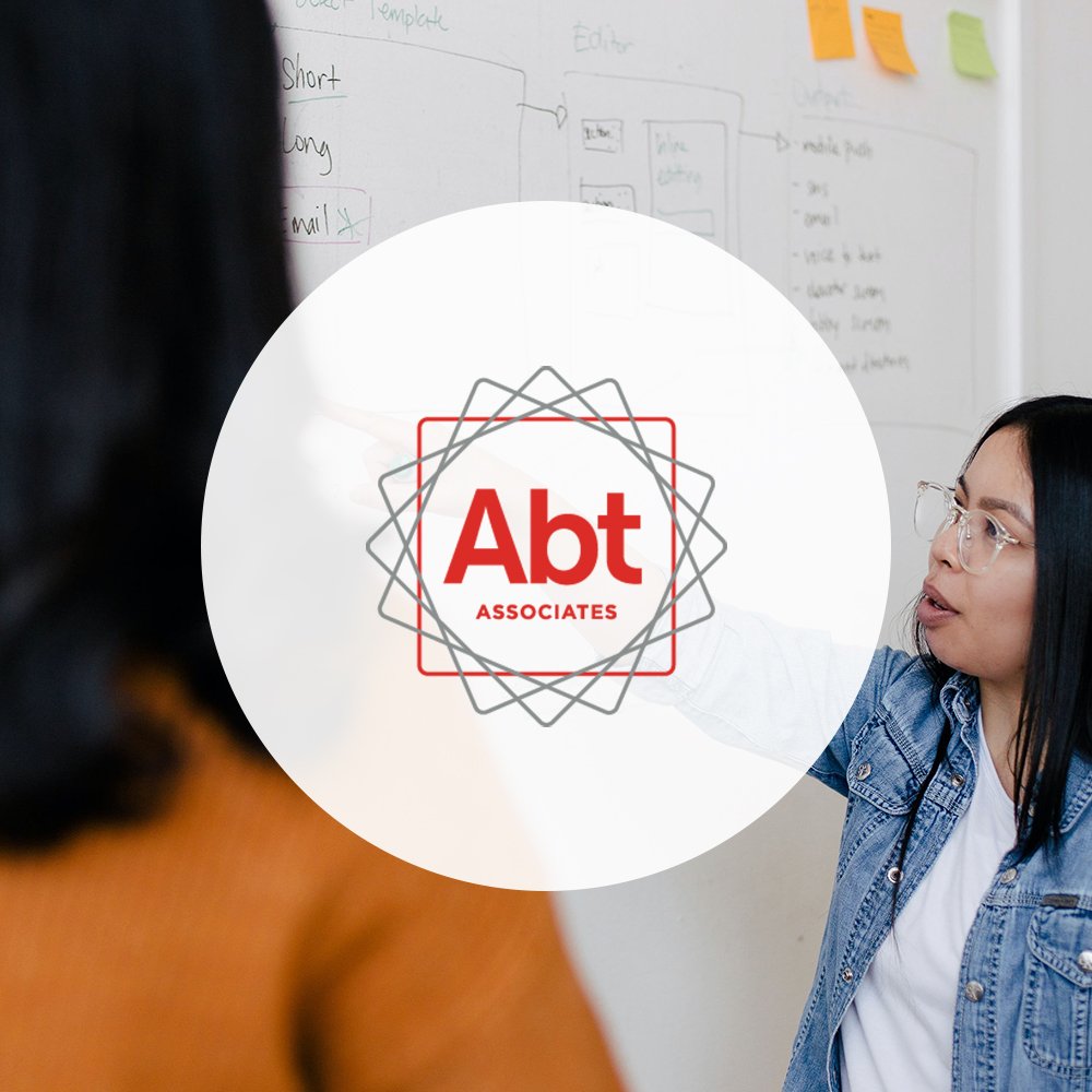 Abt Associates logo over two people working with a white board